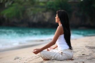 Photo: Woman Meditating on the Beach