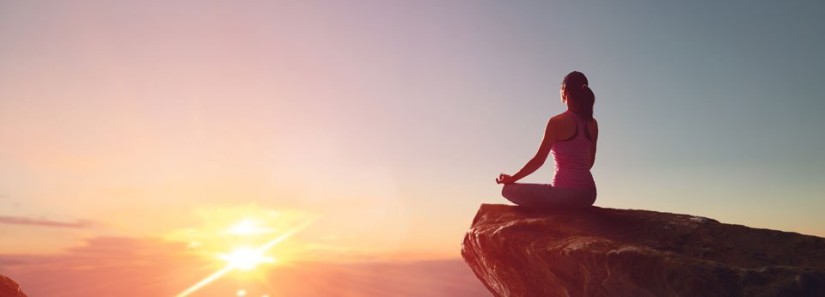 Photo: Woman meditating at sunset